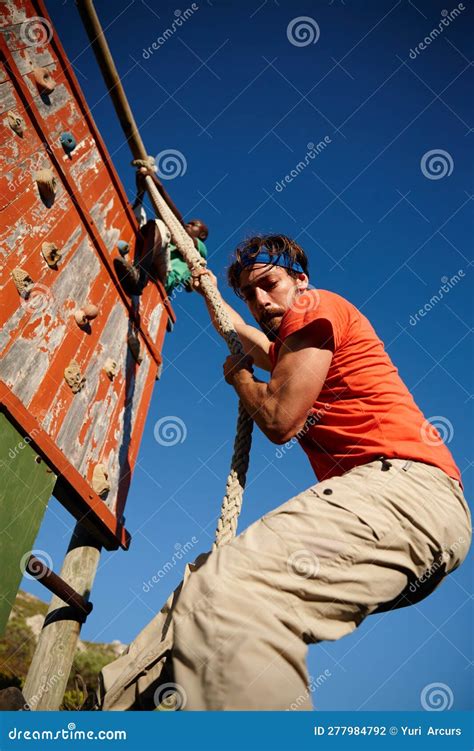 Endure And Conquer A Young Man Climbing Over An Obstacle At Military