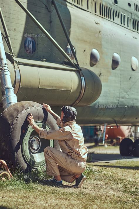 Mechanic In Uniform And Flying Helmet Wash Large Military Helicopter