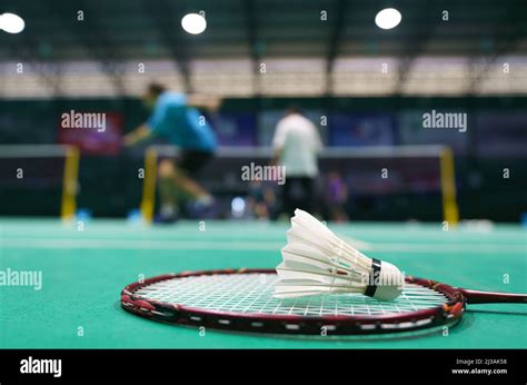 Shuttlecock On Green Badminton Playing Court With Player In Background